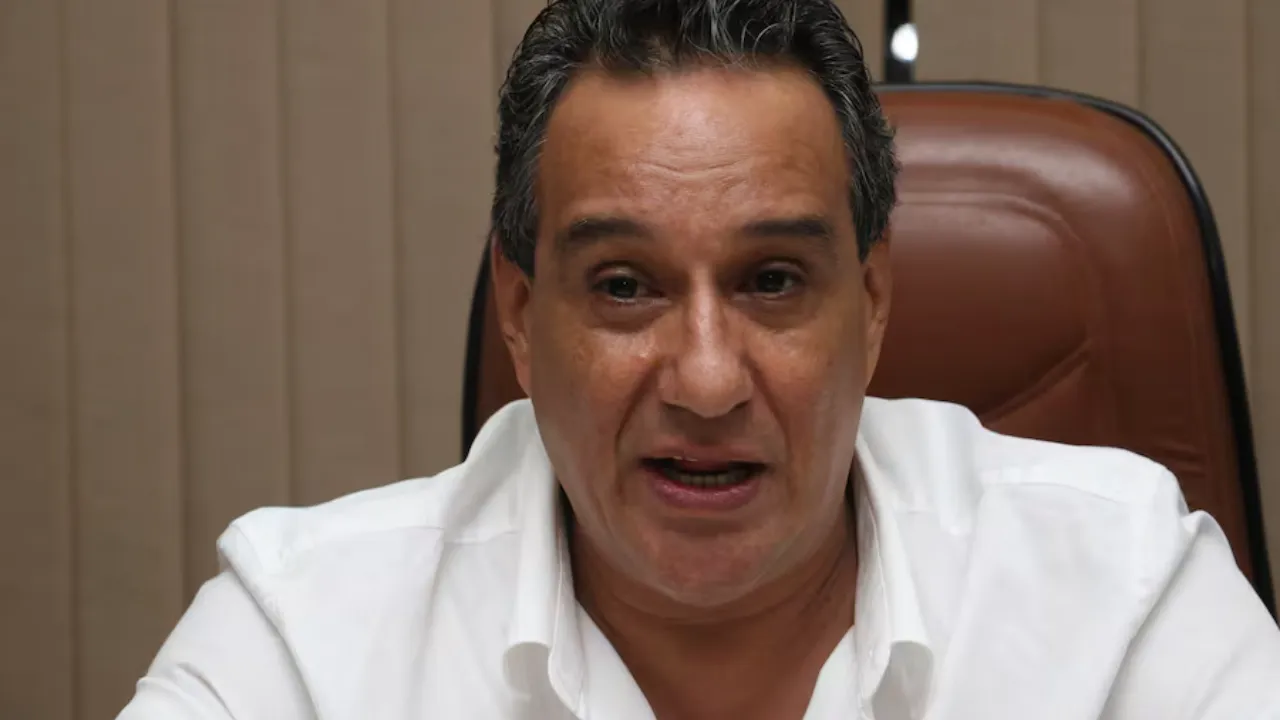 Primer plano de Hugo Javier González con camisa blanca, sentado en una silla de cuero marrón mirando de frente.