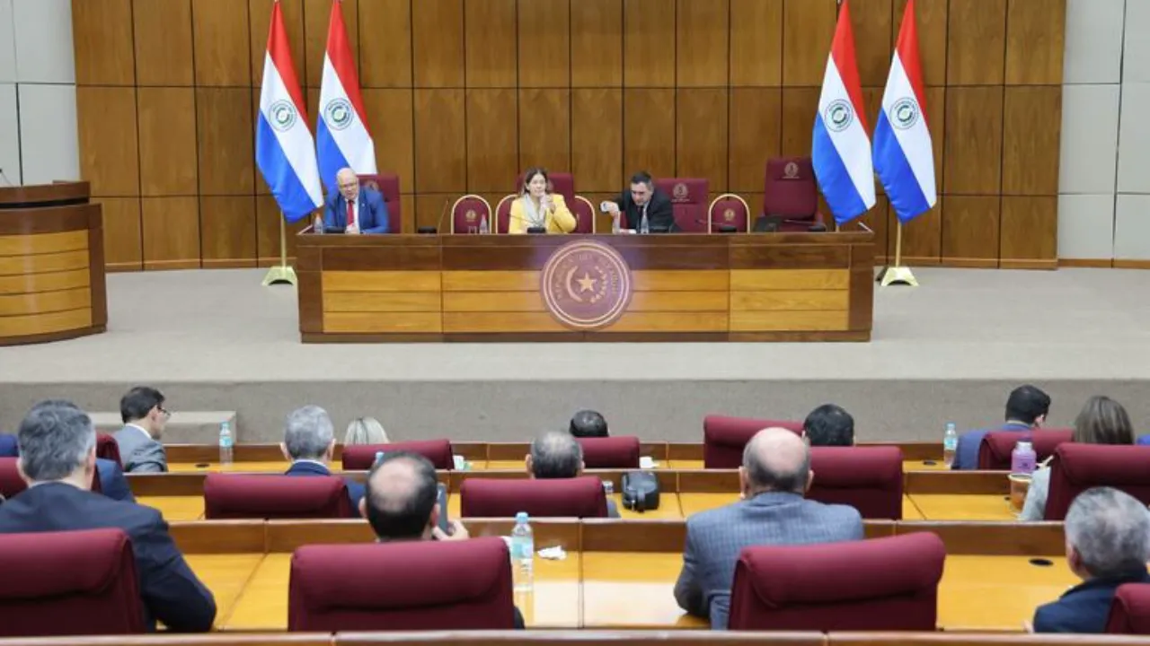 Autoridades en una mesa directiva con banderas de Paraguay exponen ante legisladores en una sala del Congreso.