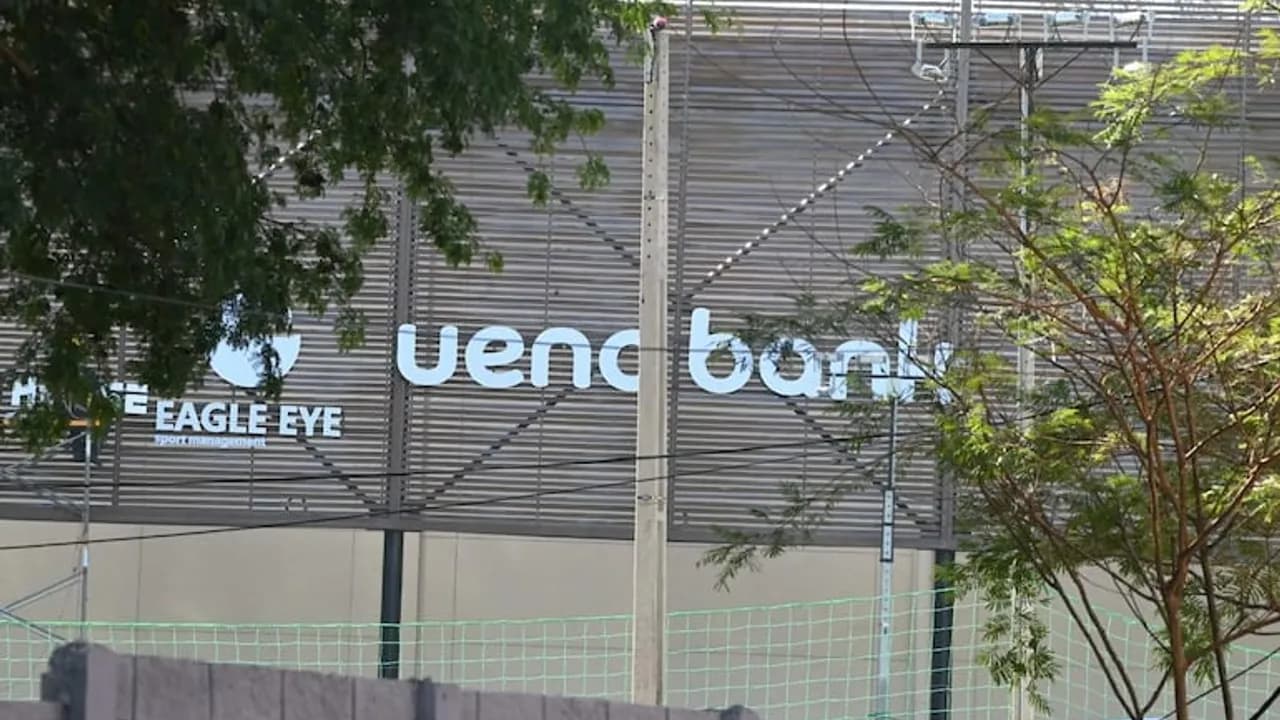 Letrero de ueno bank y Eagle Eye en la fachada de un edificio, detrás de ramas de árboles y una red verde.