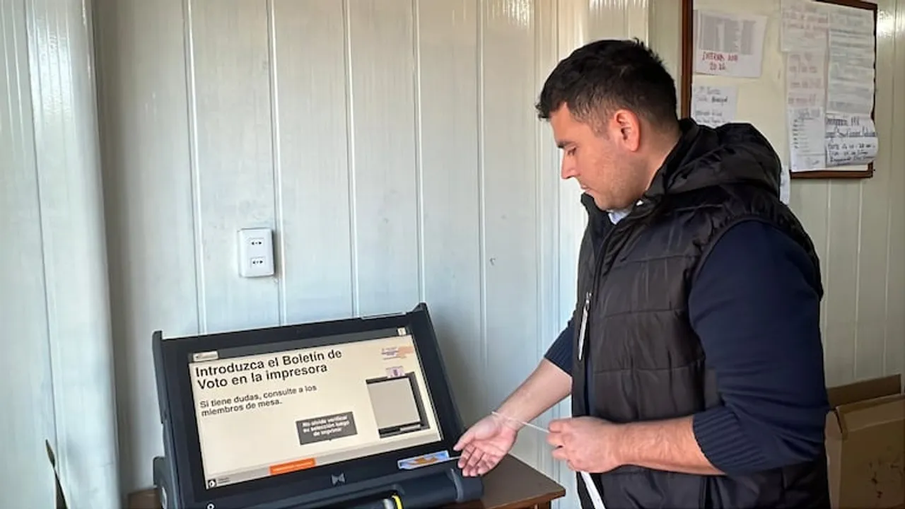 Un hombre de perfil junto a una máquina de votación electrónica con instrucciones en pantalla en Paraguay.
