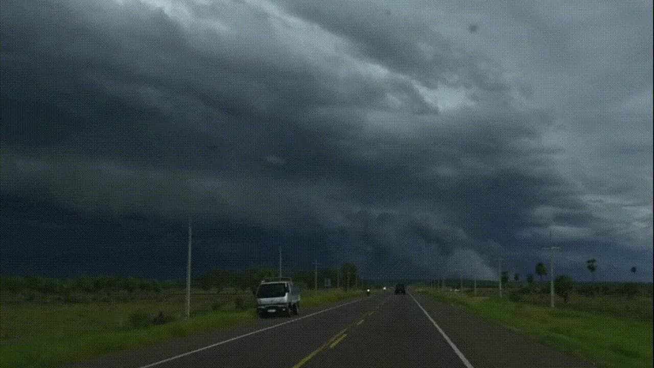 Carretera asfaltada bajo un cielo cubierto por densas y oscuras nubes de tormenta en el campo.