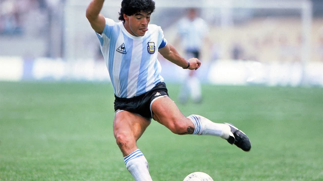 Diego Maradona con la camiseta de la selección argentina patea una pelota de fútbol en un campo de juego.