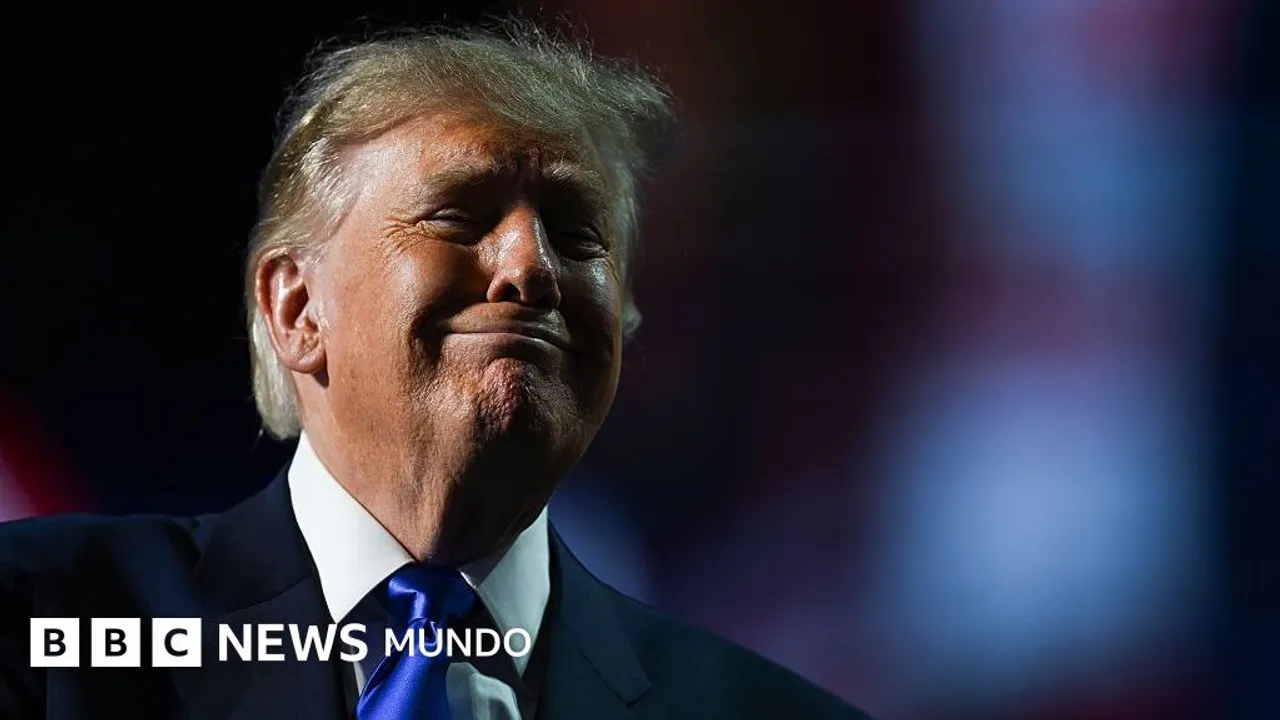 Donald Trump sonríe vistiendo un traje oscuro y una corbata azul brillante sobre un fondo oscuro difuminado.