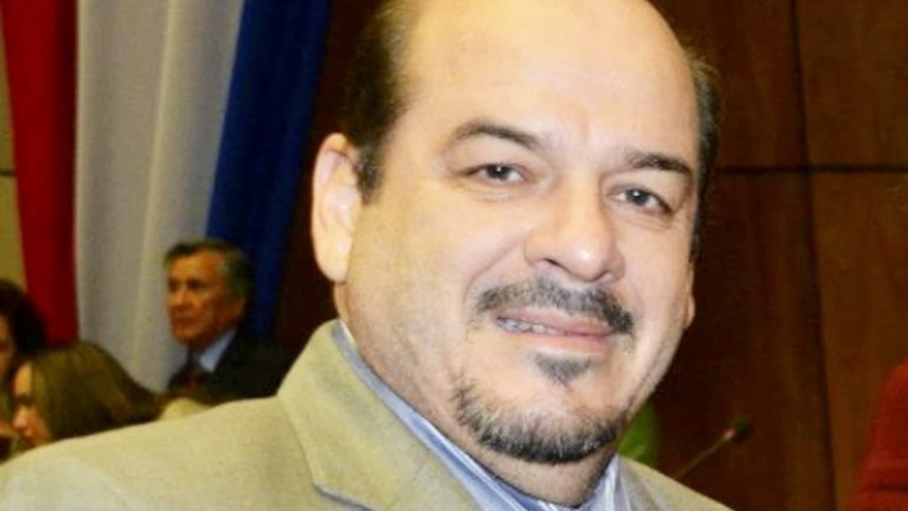 Primer plano de Miguel Ángel Robles sonriendo, con barba de candado y vistiendo un saco de color claro.
