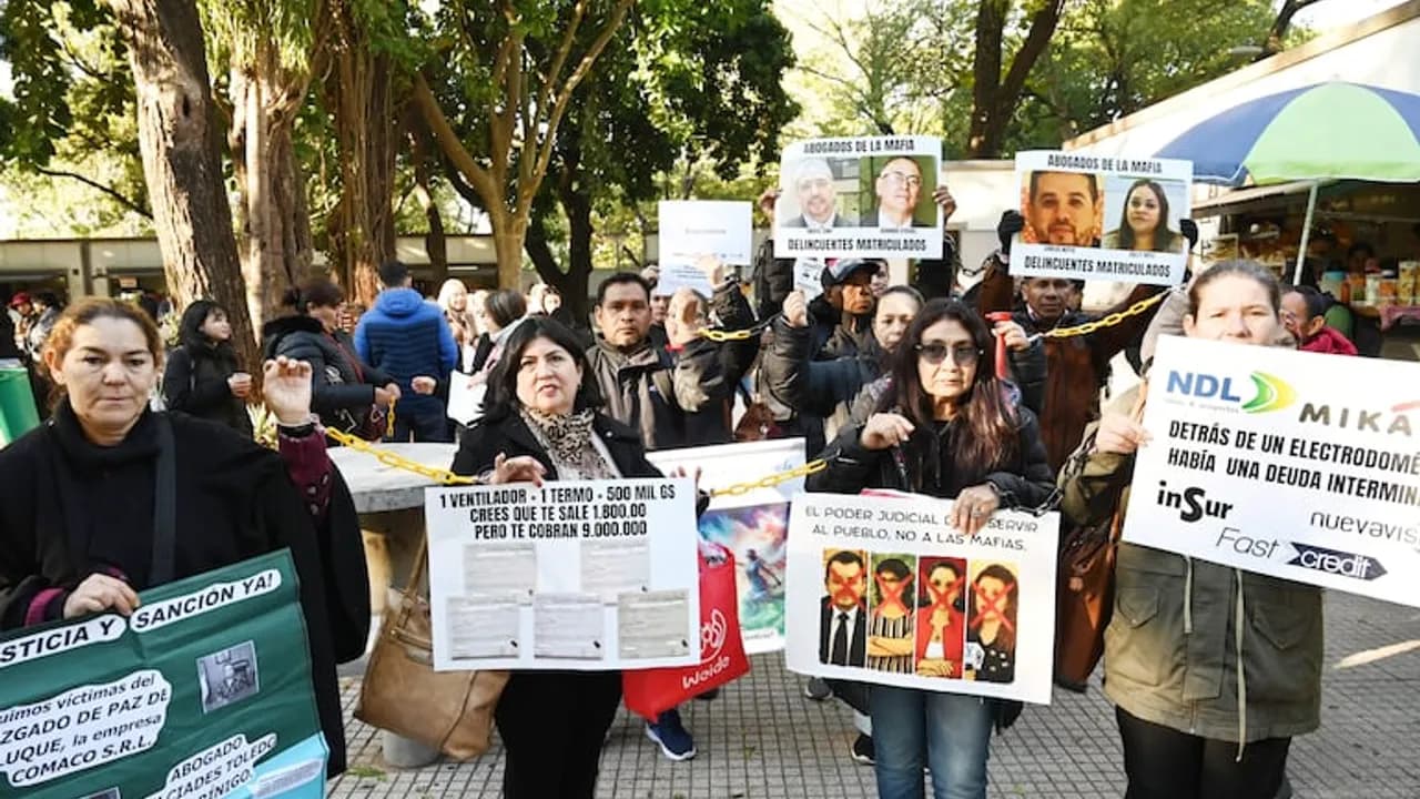 Manifestantes sostienen pancartas de protesta contra la mafia de los pagarés y exigen justicia en la vía pública.