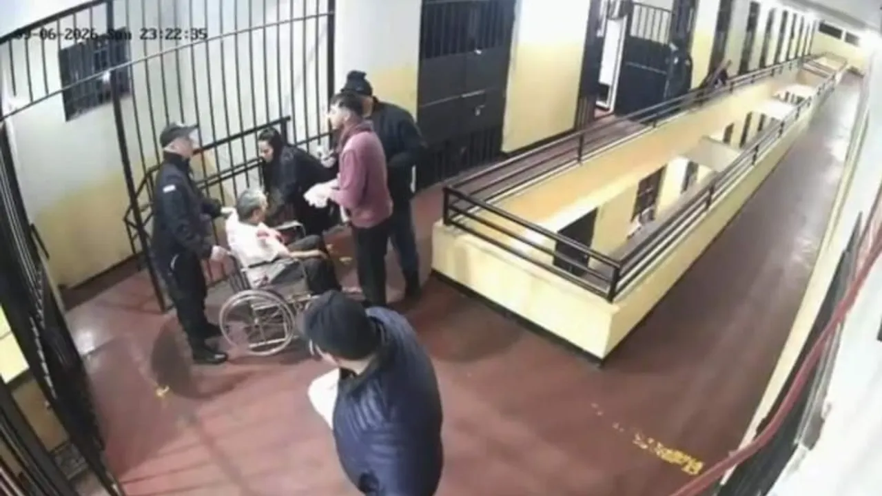 Varios uniformados y civiles asisten a un hombre en silla de ruedas en el pasillo de un establecimiento.