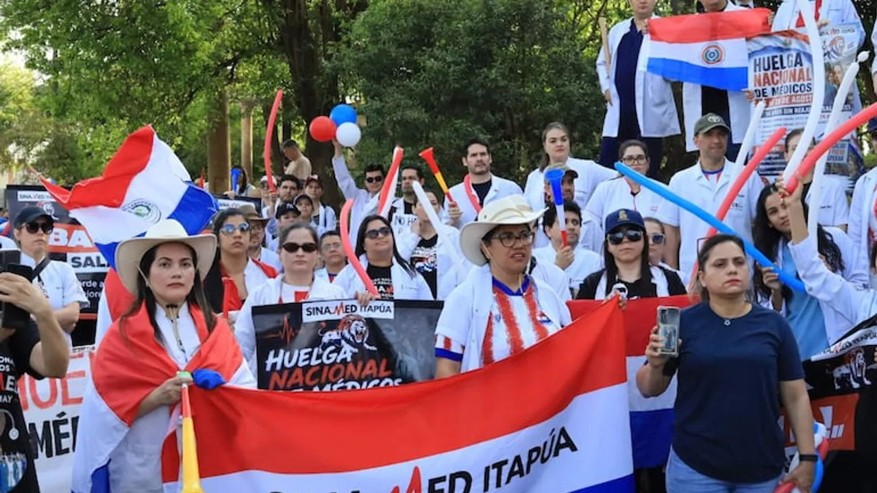 Médicos con batas blancas sostienen banderas paraguayas y un cartel de la huelga nacional de SINAMED Itapúa.