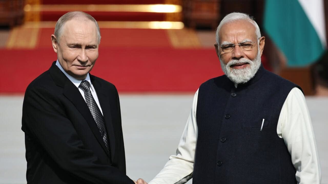 Vladimir Putin y Narendra Modi se dan la mano sonriendo durante un encuentro oficial.