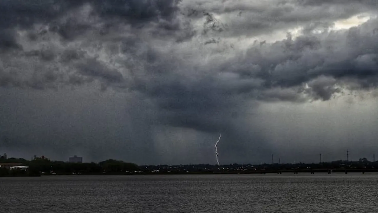 Cielo cubierto de densas nubes grises de tormenta sobre un río con un rayo cayendo a lo lejos.