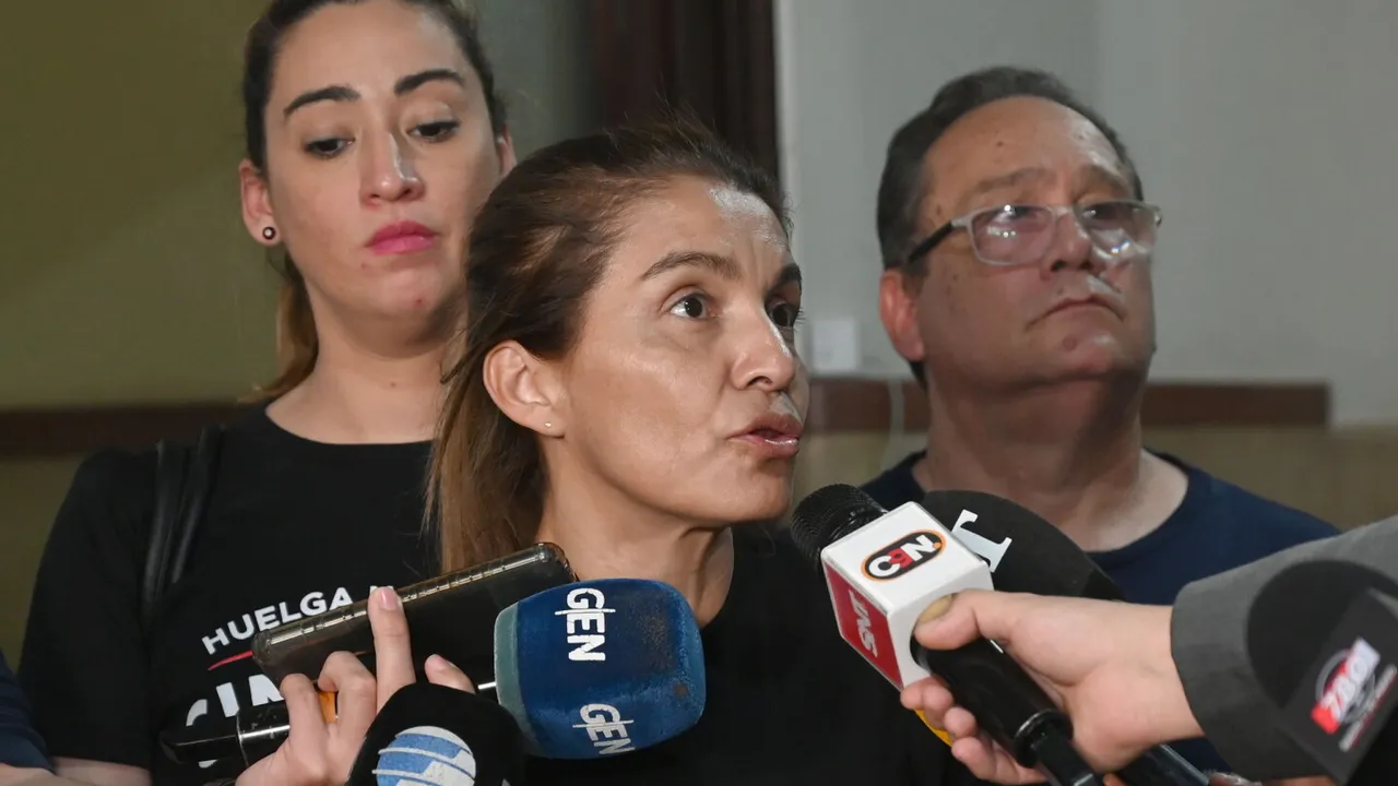 Una mujer habla ante varios micrófonos de prensa de canales paraguayos mientras otras personas la observan detrás.
