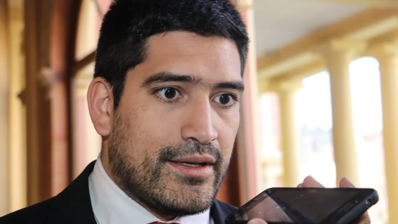 Mauricio Espínola con traje oscuro y corbata naranja declara frente a micrófonos de prensa.