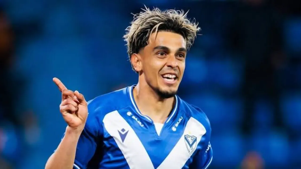Ronaldo Martínez sonríe y levanta el dedo índice festejando con la camiseta azul y blanca de Vélez Sarsfield.