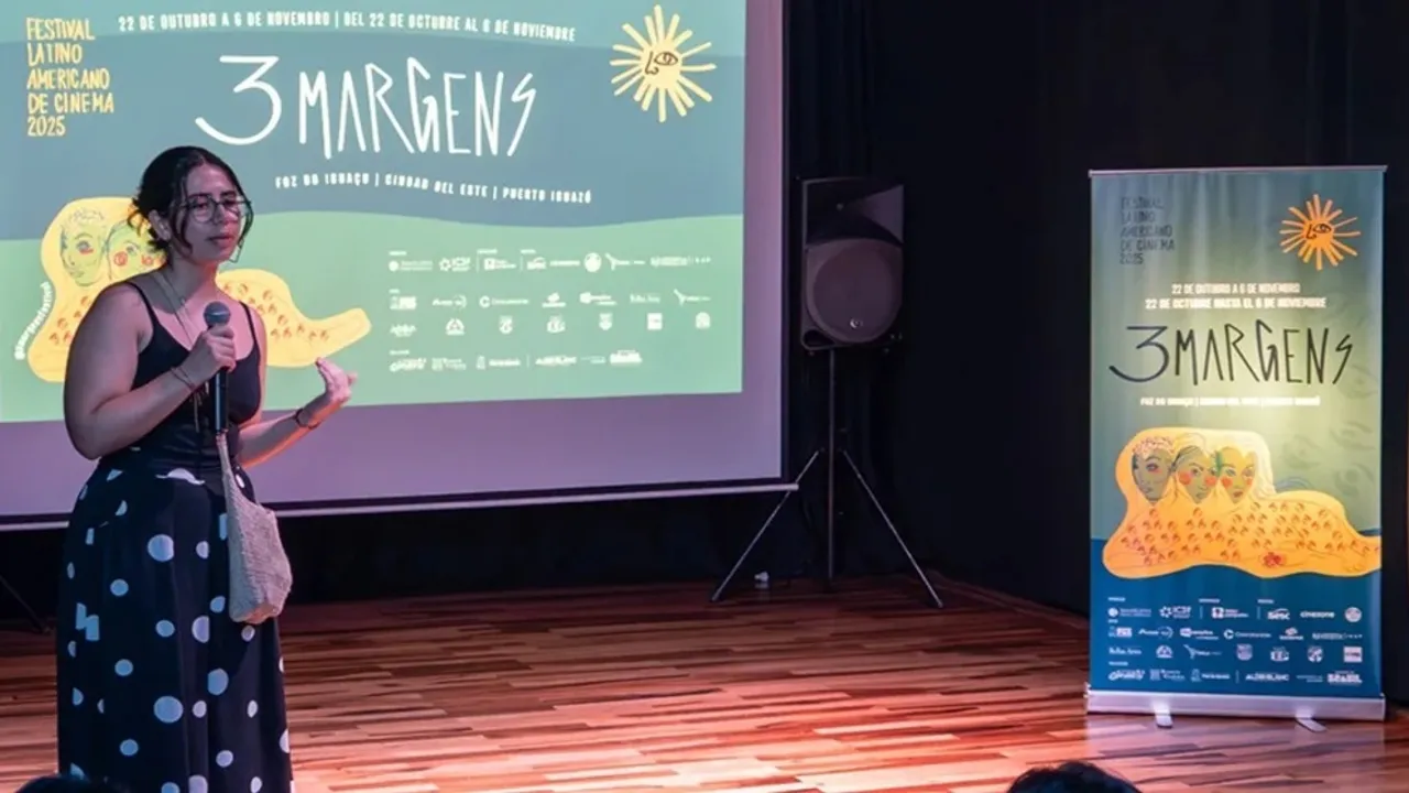 Mujer hablando con micrófono en mano frente a una pantalla con el afiche de 3 Margens Festival