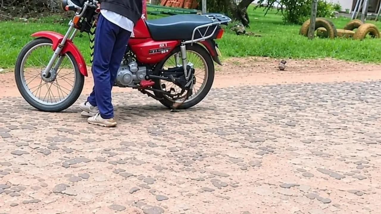 Motocicleta roja estacionada sobre una calle empedrada en una zona residencial de Paraguay.