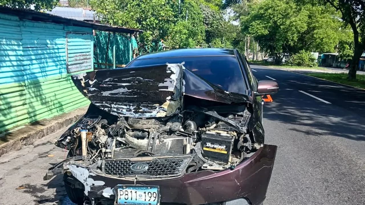 Automóvil particular de color oscuro con la parte delantera totalmente destruida por un choque vial.