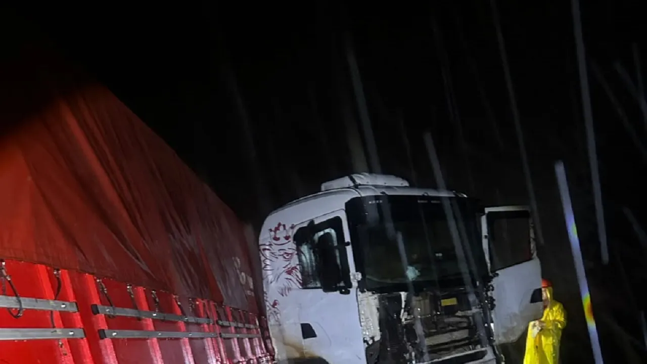 Cabina blanca de un camión Scania dañada al costado de la ruta de noche junto a un socorrista con impermeable