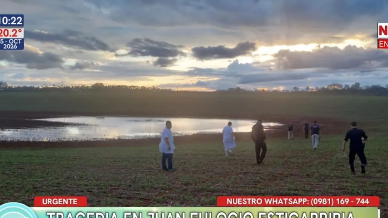 Personas y agentes policiales caminan por un campo abierto hacia un tajamar con agua al atardecer en Caaguazú.