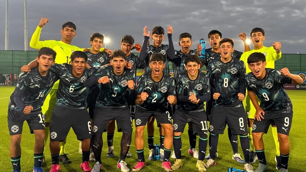 Jóvenes futbolistas del seleccionado paraguayo celebran eufóricos en la cancha luciendo sus uniformes deportivos oscuros.