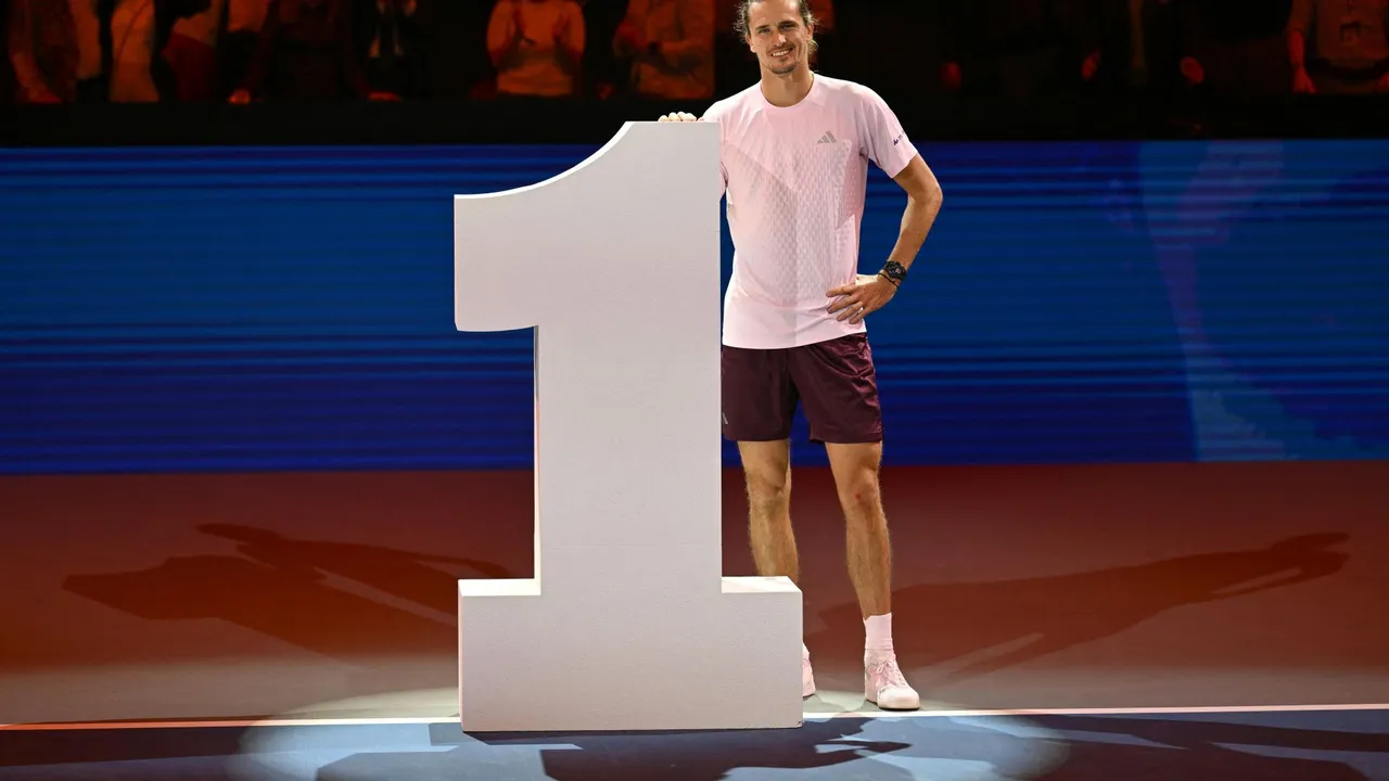 Alexander Zverev posa de pie sonriente junto a una enorme escultura blanca con forma de número uno en la pista.
