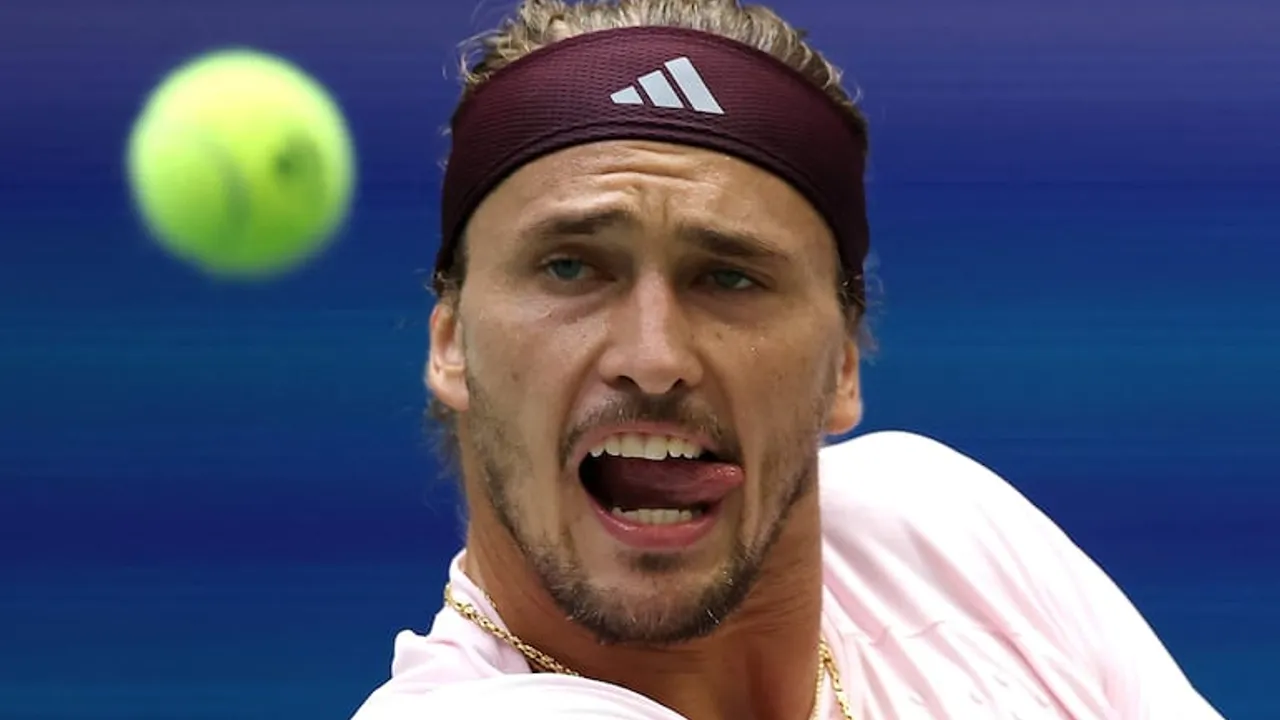 Tenista con vincha deportiva granate y camiseta clara gesticula con la lengua afuera mientras una pelota se acerca.