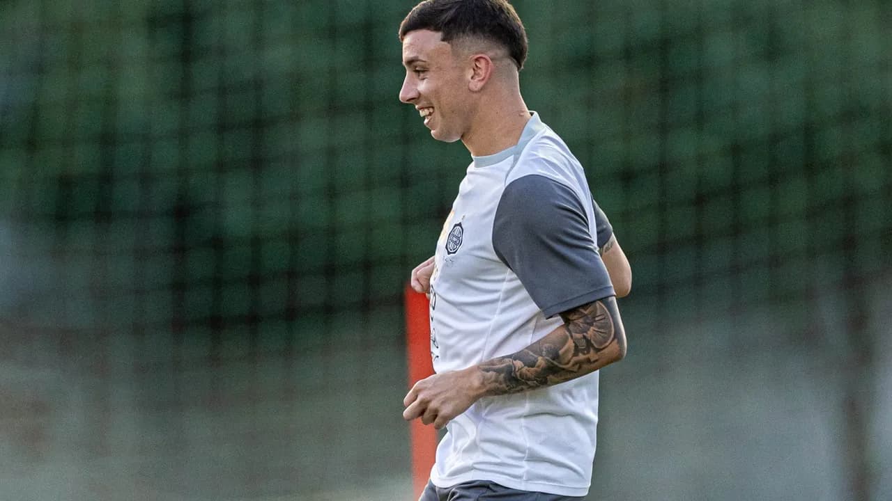 El futbolista Franco Alfonso corre sonriente durante una práctica con indumentaria del Club Olimpia sobre el césped.