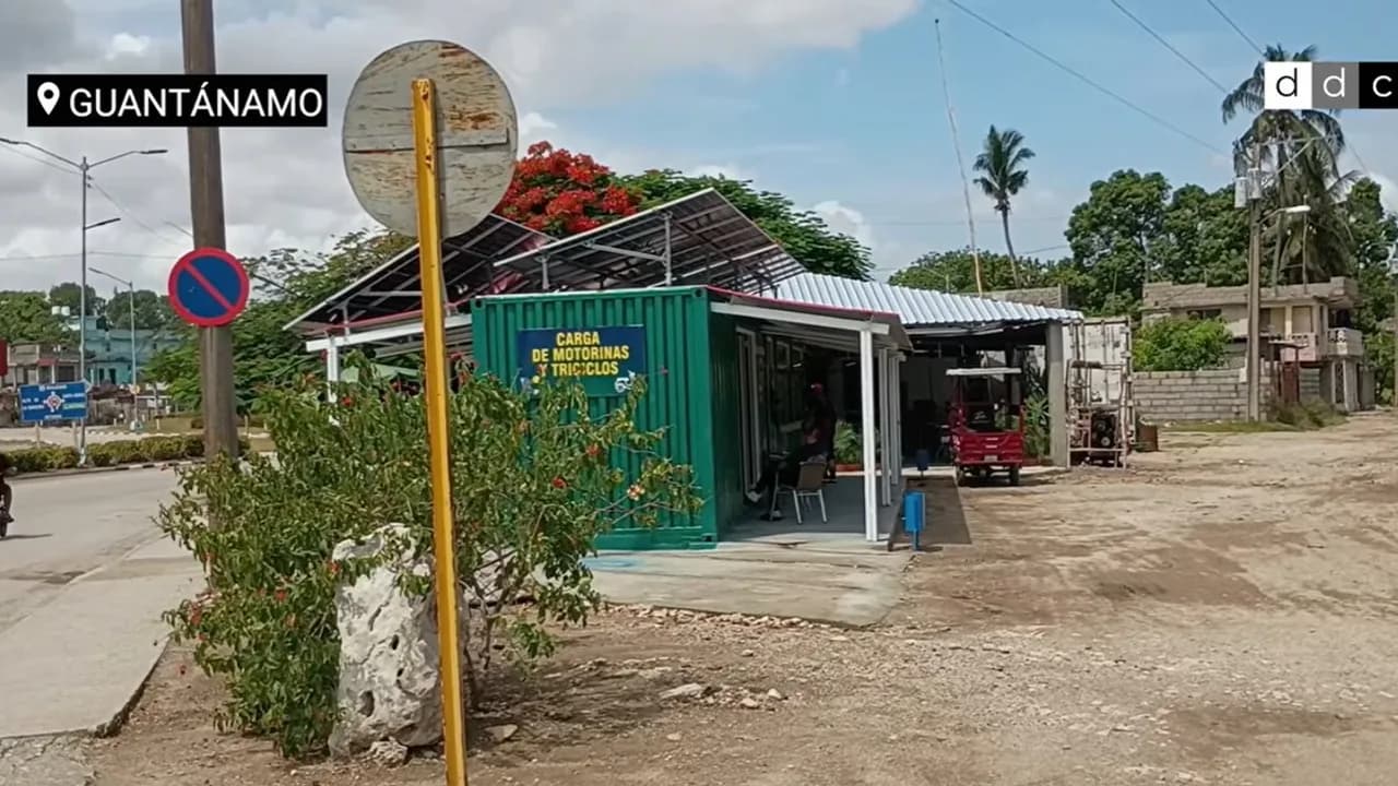 Módulo contenedor verde con paneles solares en el techo y cartel de carga para vehículos eléctricos en Guantánamo.