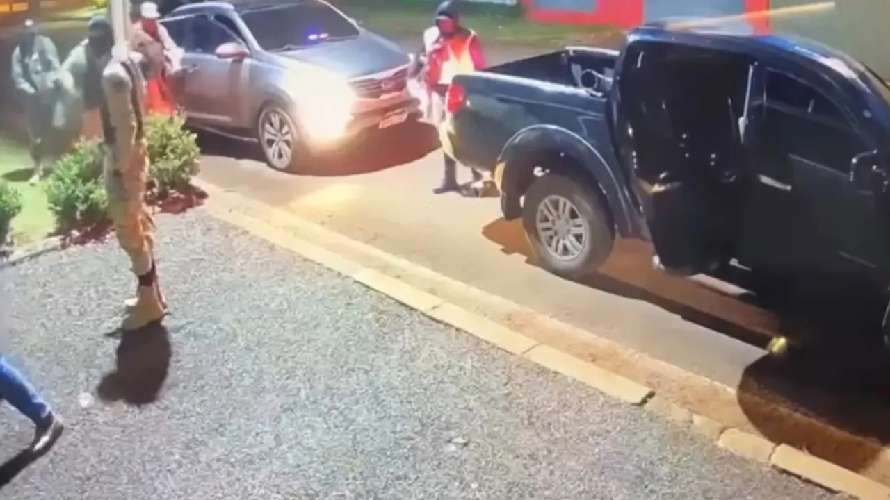Personas con uniformes tácticos y chalecos se despliegan junto a dos camionetas frente a una vivienda durante la noche.