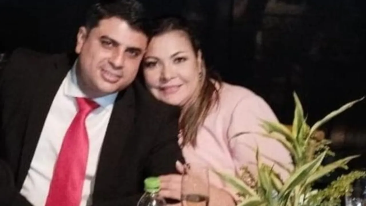 Un hombre de traje oscuro y corbata roja posa sonriente junto a una mujer vestida con una prenda clara.