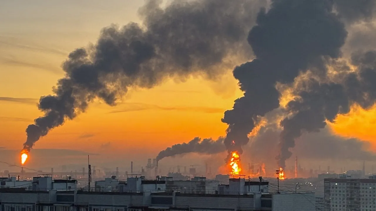 Columnas de humo negro y llamaradas emergen de una refinería durante el atardecer tras un ataque con drones.