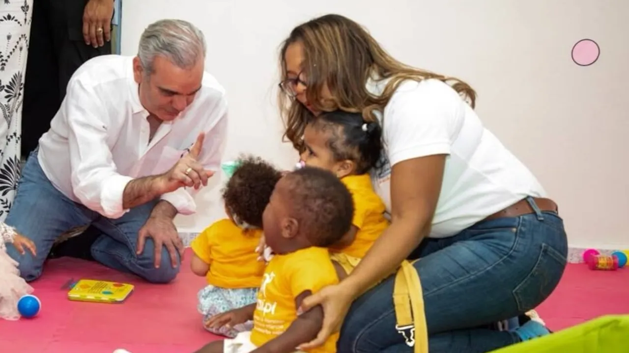Adultos interactúan en el suelo con niños pequeños en una sala de juegos con colchonetas.