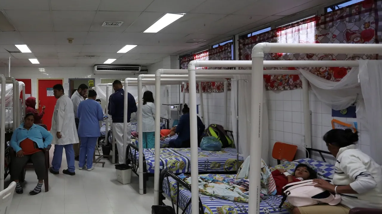 Sala hospitalaria con camas con mosquiteros, pacientes acostados y personal de salud con batas blancas caminando.