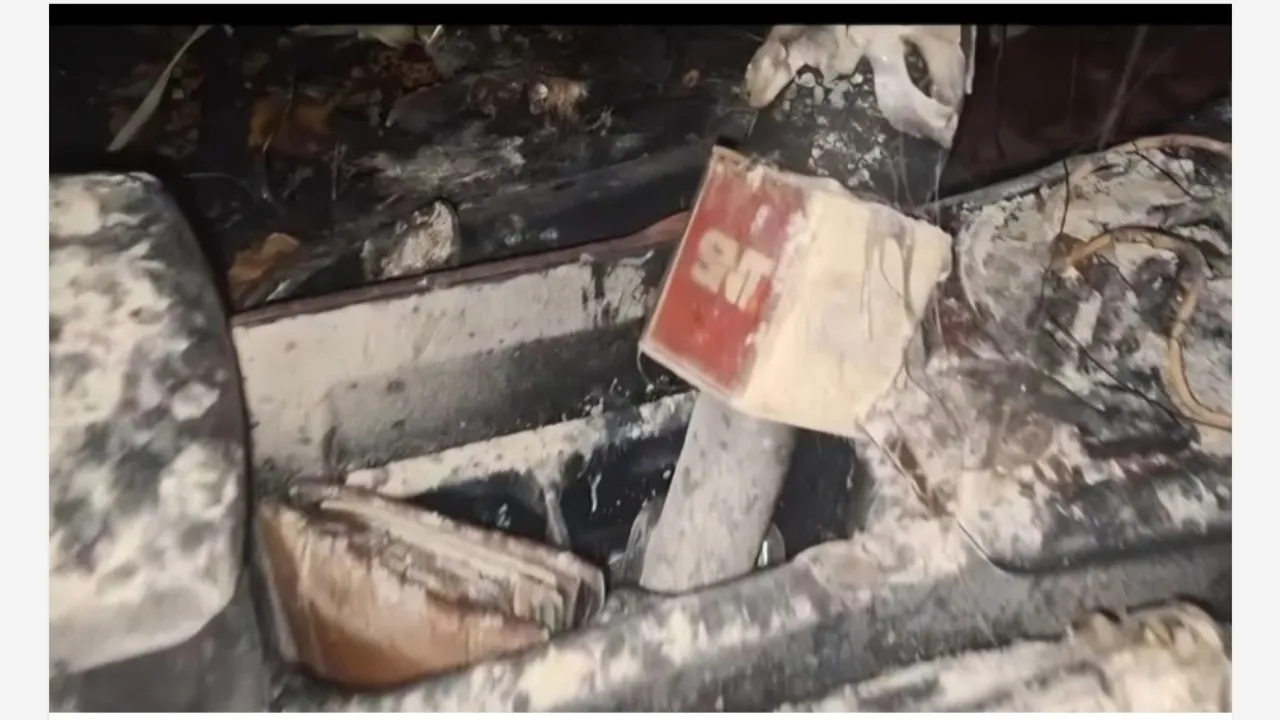 Interior quemado de un automóvil cubierto de hollín con restos de un micrófono periodístico dañado por el fuego.