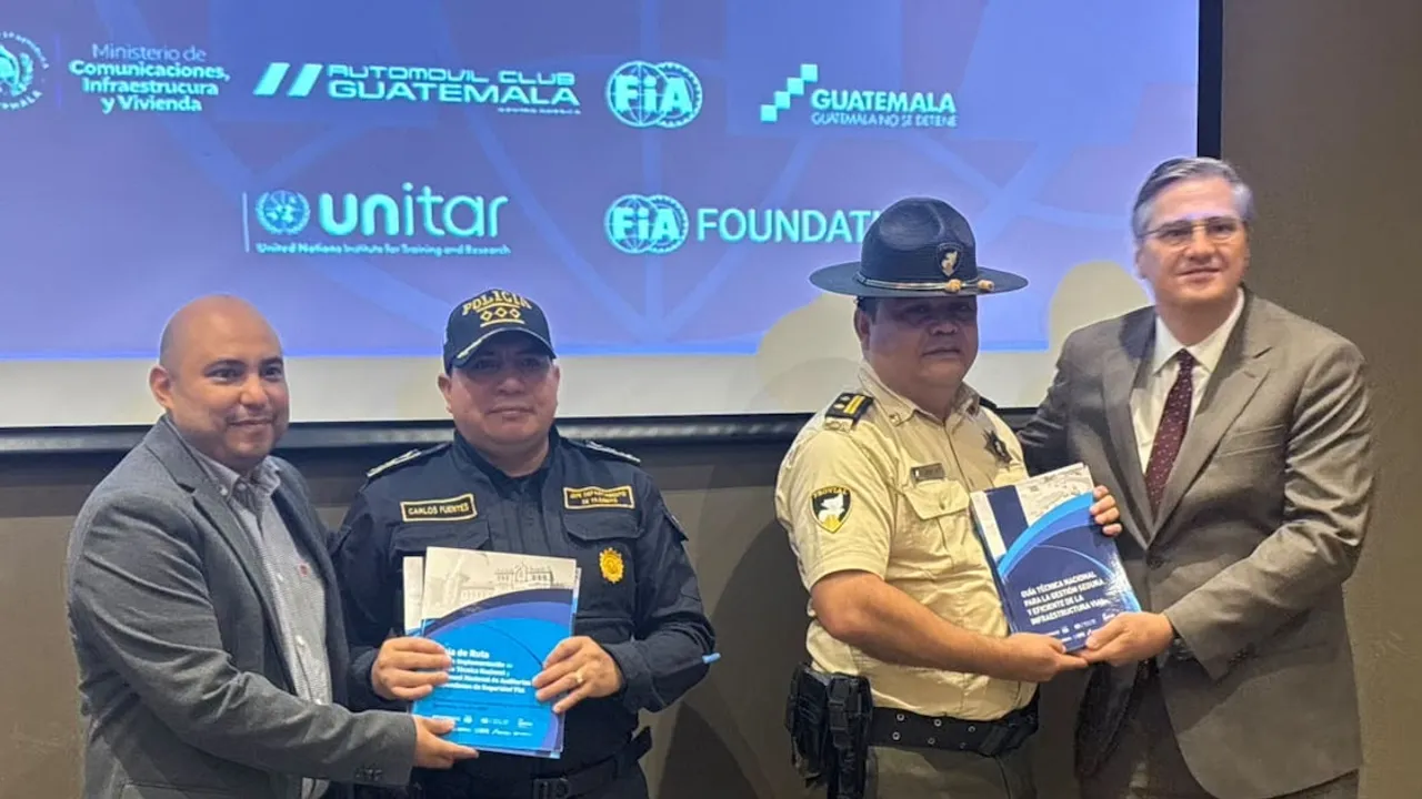 Cuatro hombres presentan manuales técnicos impresos frente a una pantalla institucional durante un acto en Guatemala.