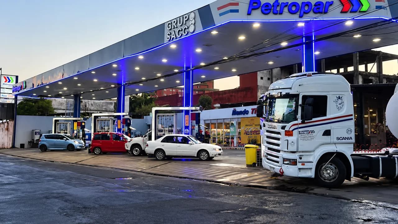 Estación de servicios Petropar con vehículos y un camión blanco cargando combustible bajo la marquesina iluminada.