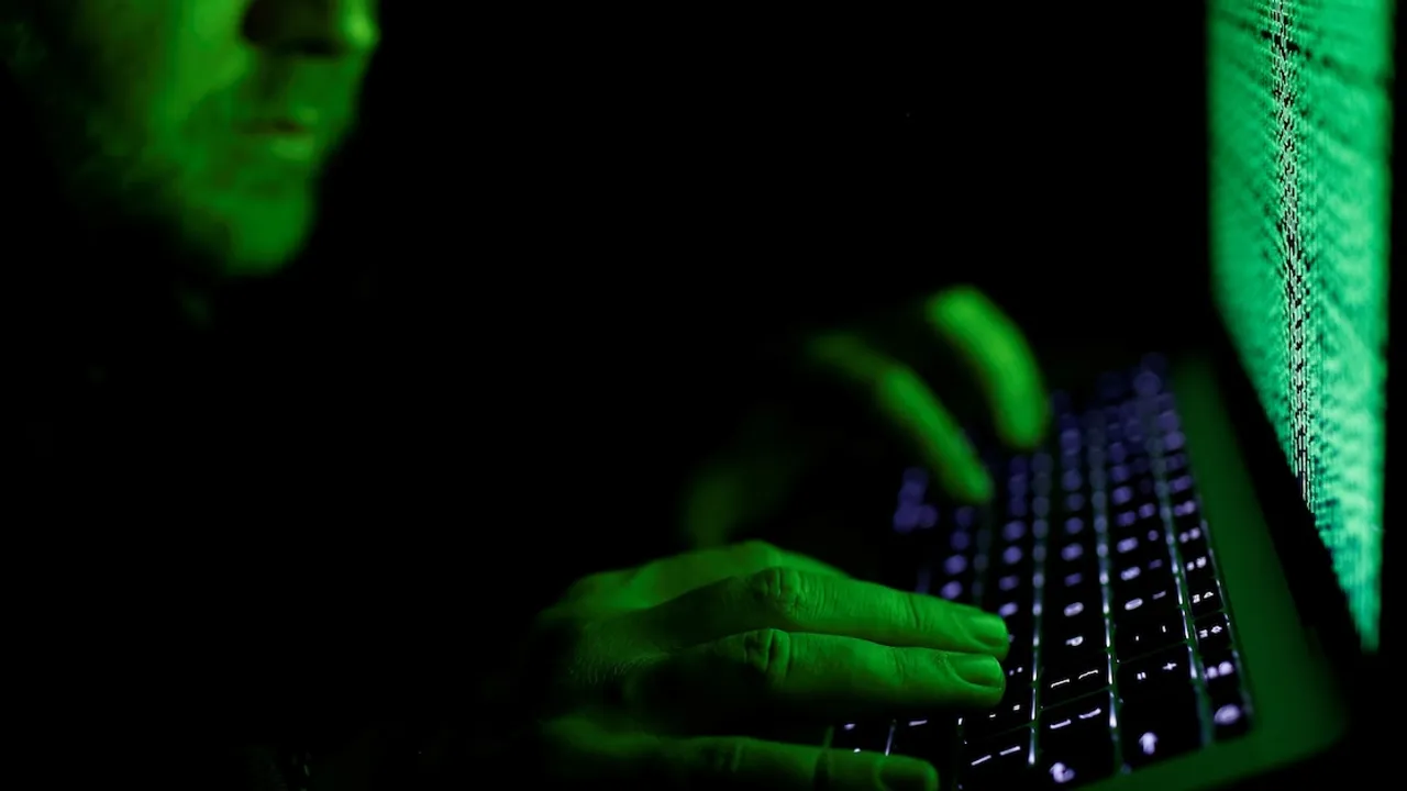 Manos escribiendo en el teclado de una computadora portátil iluminada en tonos verdes en una habitación oscura