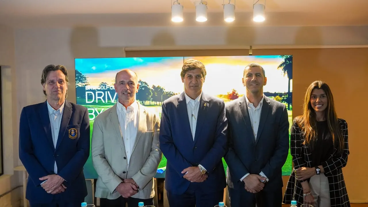 Cinco directivos formales posan frente a una pantalla con un campo de golf durante la presentación oficial.