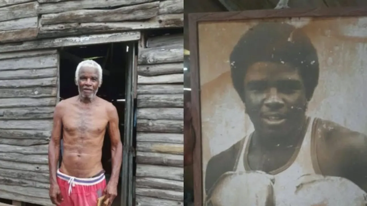 Un hombre mayor sin camiseta junto a la foto enmarcada de un joven púgil con guantes de boxeo.