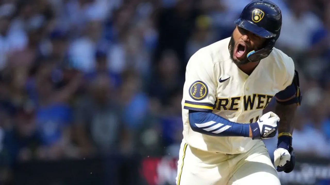 Pelotero de los Brewers con casco azul y uniforme blanco festeja una jugada gritando de emoción en el campo.