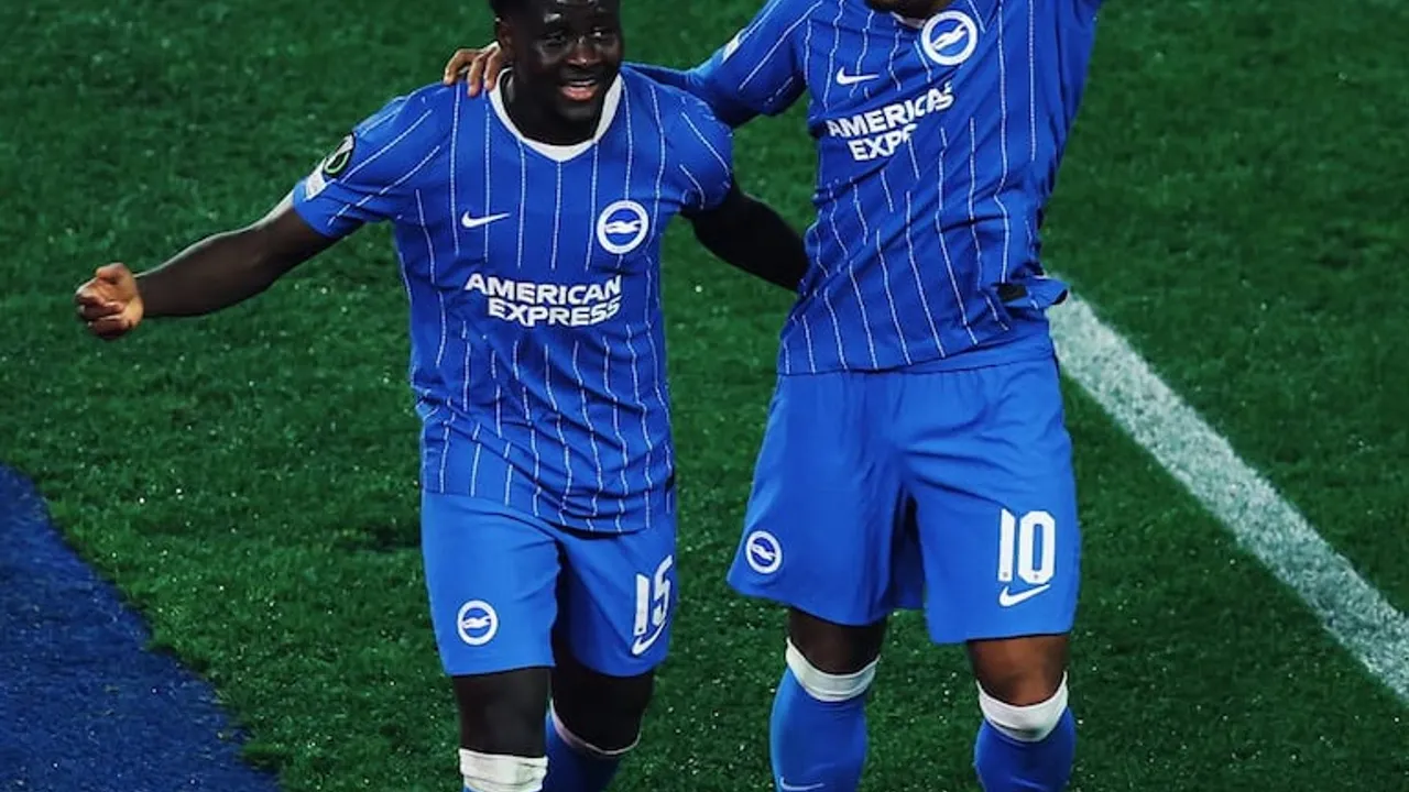 Dos jugadores del Brighton con uniforme azul celebran un gol sonrientes sobre el césped durante el partido