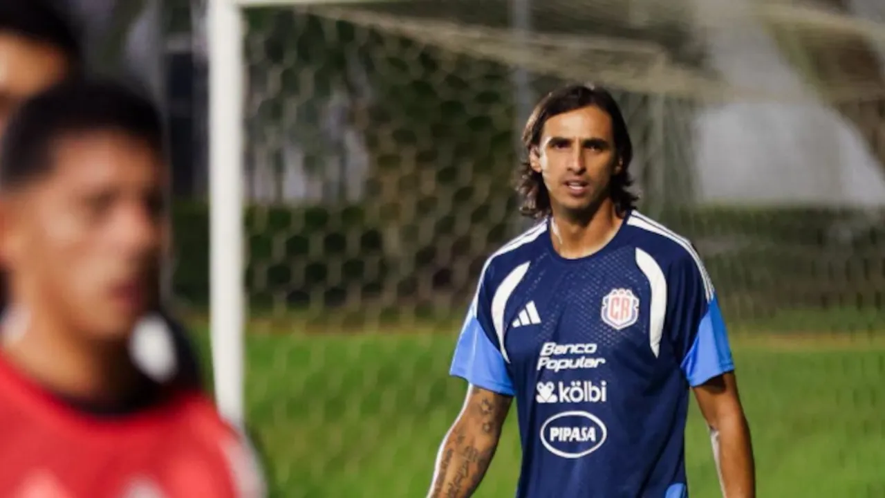 Bryan Ruiz con indumentaria deportiva azul durante una práctica en un campo de fútbol con arquería al fondo.