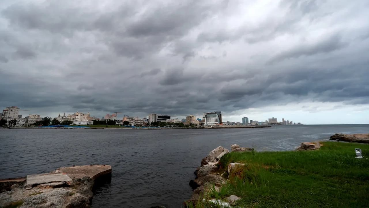 Cielo cubierto de nubarrones oscuros sobre el mar frente al perfil costero de una ciudad portuaria.