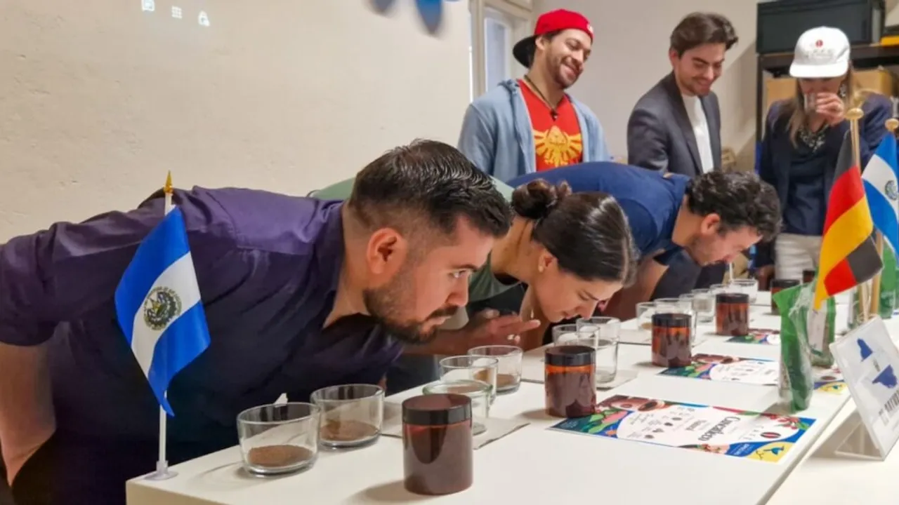 Personas se inclinan sobre una mesa para oler muestras de café molido frente a pequeñas banderas nacionales.