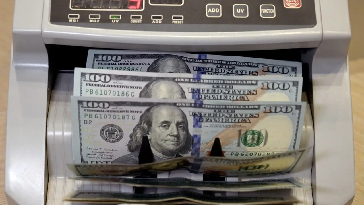 Máquina contadora eléctrica procesando varios billetes de cien dólares estadounidenses en una entidad financiera.