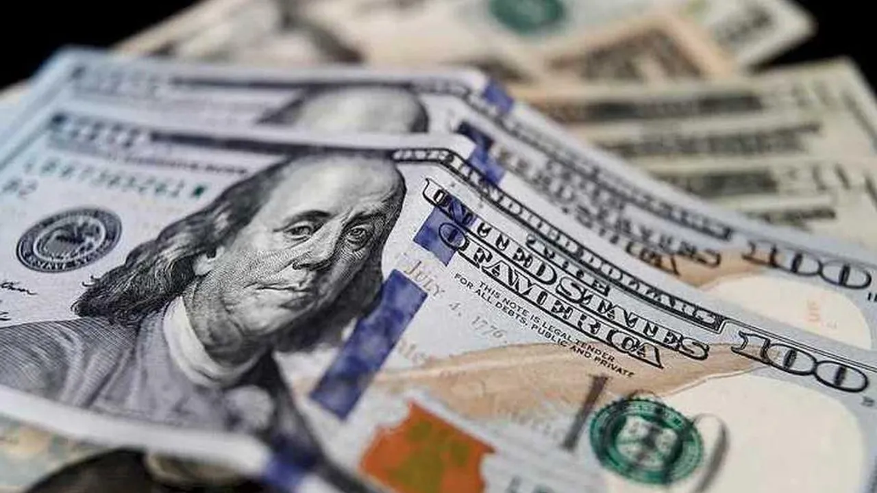 Varios billetes de cien dólares estadounidenses apilados en primer plano sobre una superficie oscura.