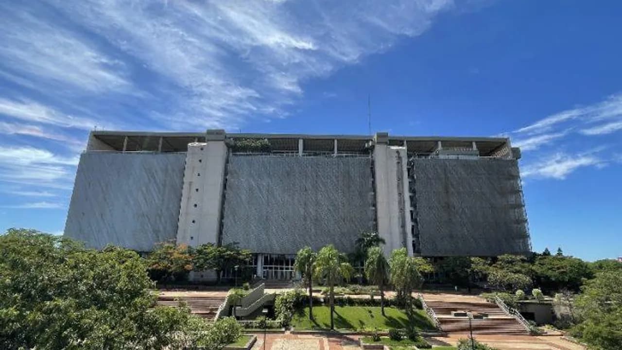 Edificio monumental de la sede central del Banco Central del Paraguay rodeado de vegetación bajo un cielo despejado.