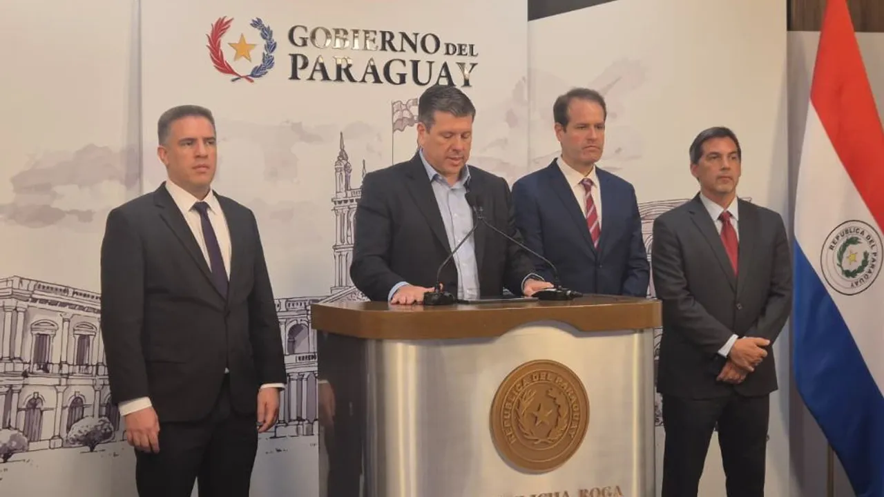 Cuatro hombres vestidos de traje formal se ubican detrás de un atril institucional durante una conferencia oficial.