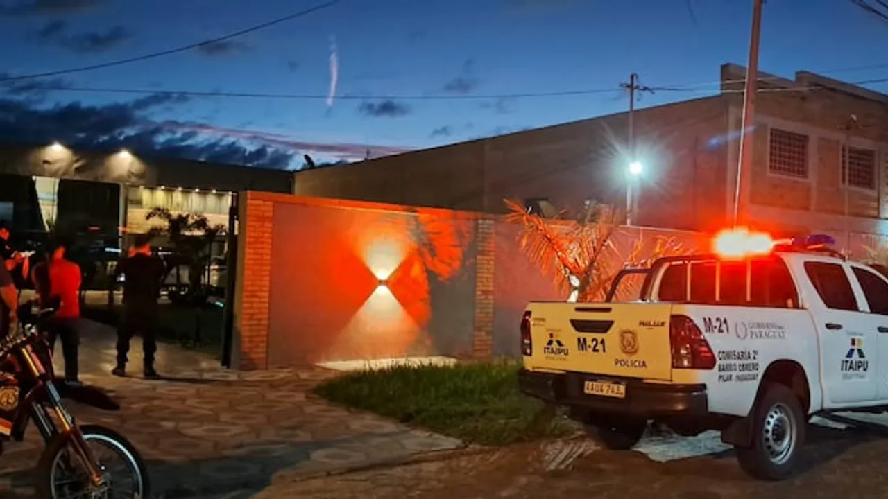Patrullera policial con luces encendidas frente a una vivienda durante un procedimiento nocturno en Pilar.