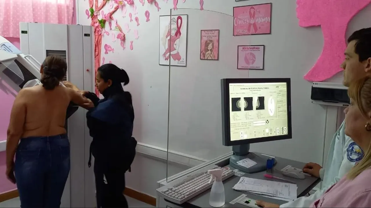 Personal de salud realiza un estudio de mamografía a una paciente frente a monitores médicos.