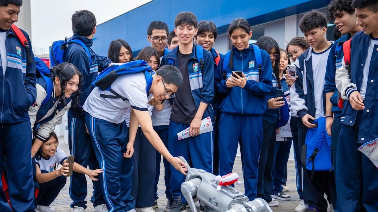 Estudiantes con uniforme deportivo observan y señalan a un robot cuadrúpedo en un patio universitario.