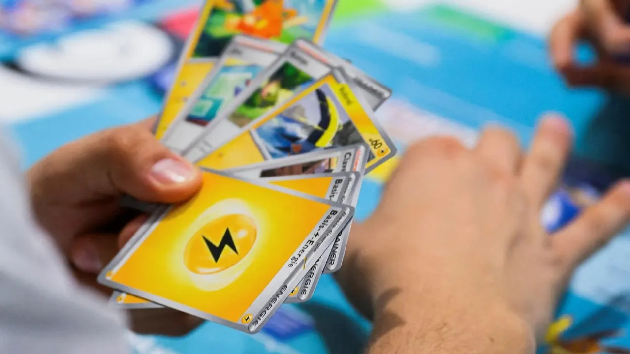 Manos de una persona sosteniendo varias cartas de juego coleccionables con ilustraciones y símbolos coloridos.